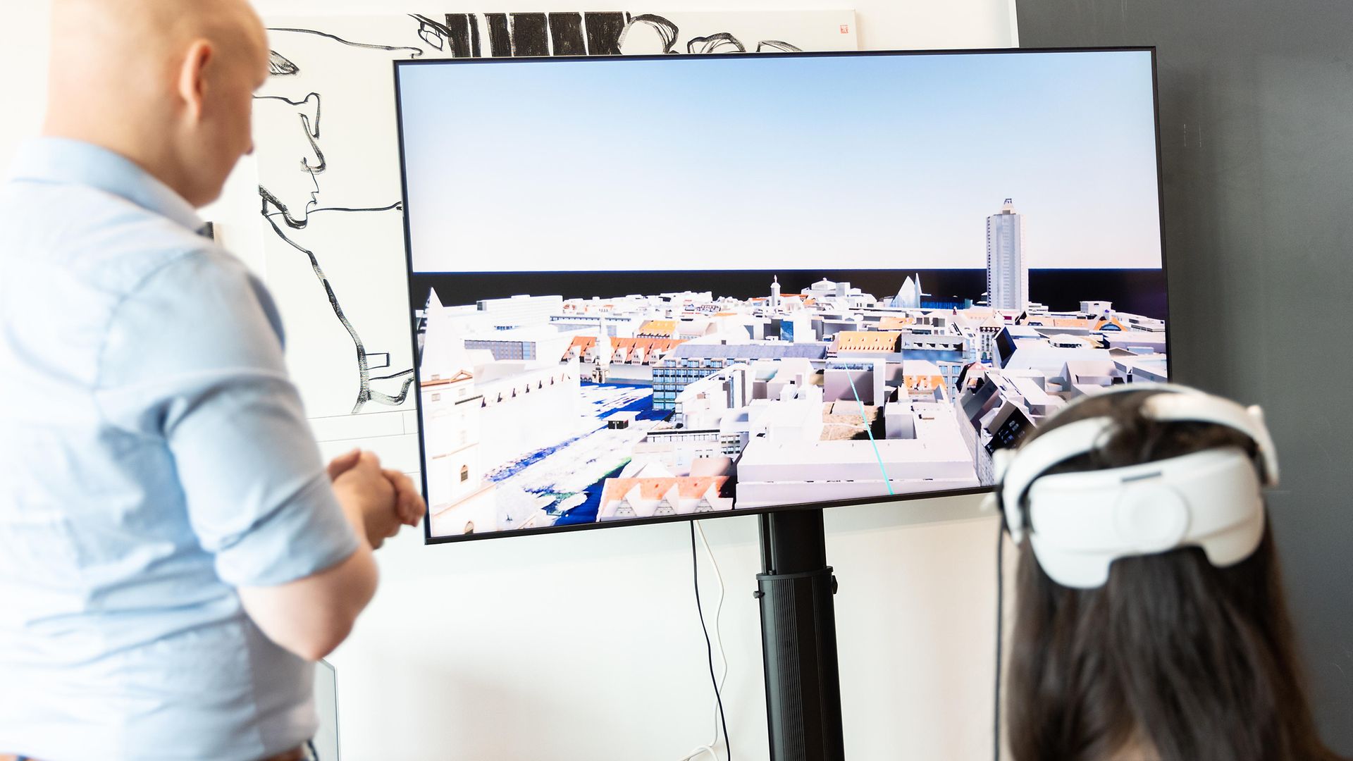 Zwei Personen vor einem digitalen Stadtmodell. Eine Frau trägt eine VR-Brille.