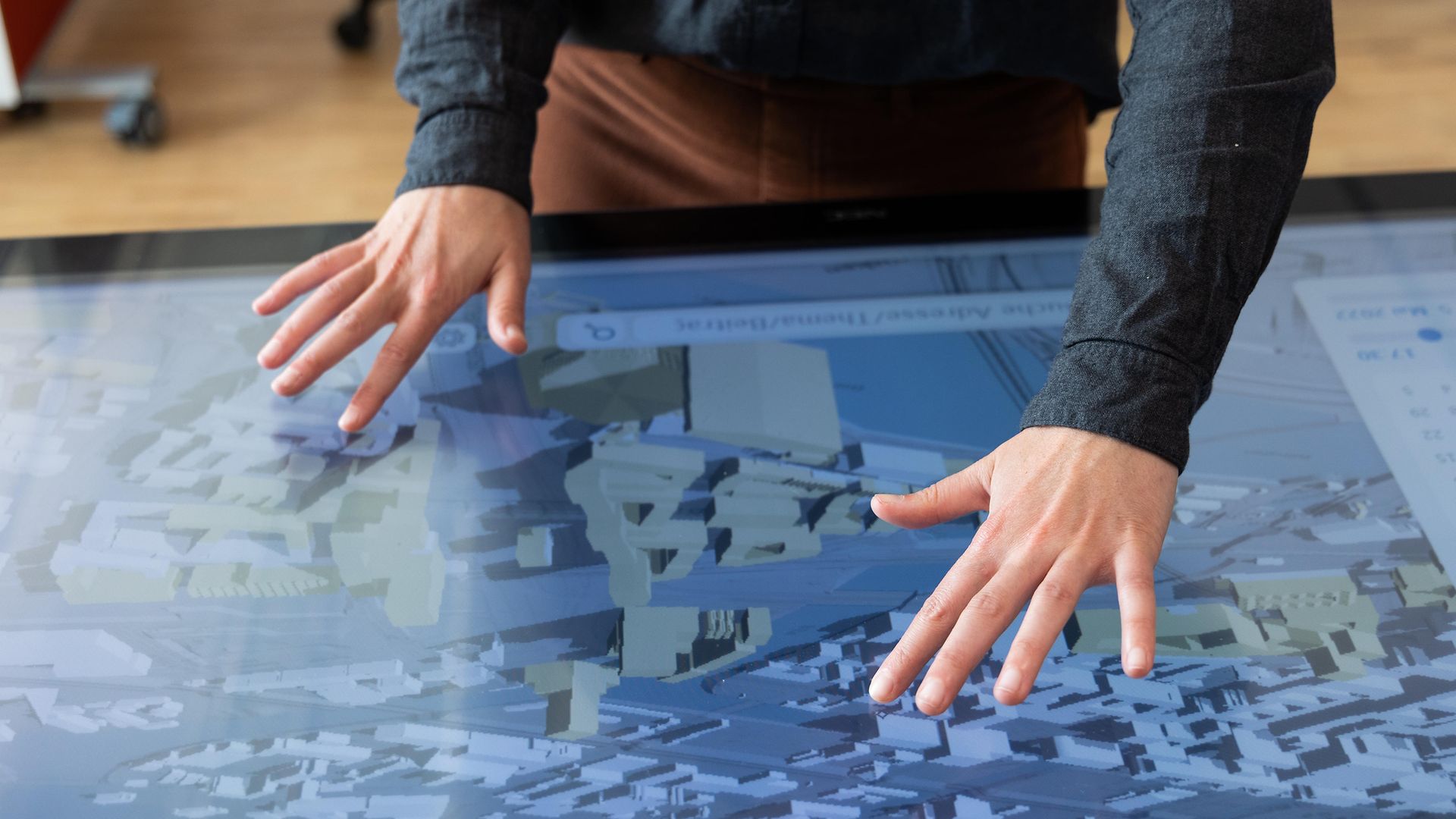 Zwei Hände tippen auf ein digitales Stadtmodell.